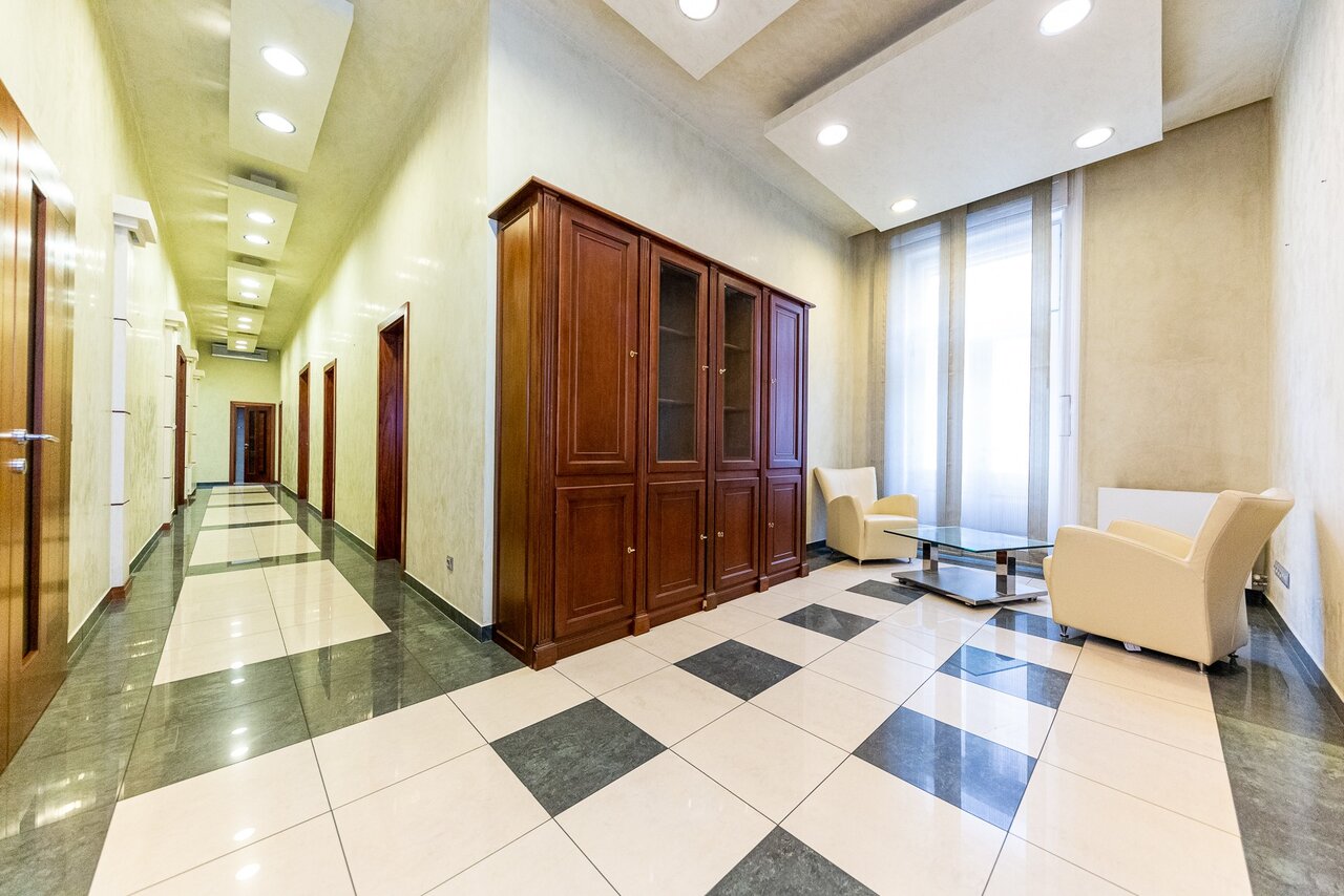 Elegáns előtér vitrines fa szekrénnyel, fotelekkel és beépített spotlámpákkal