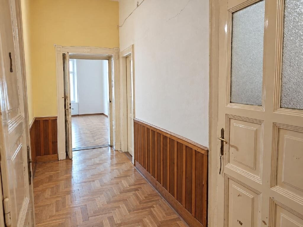 Felújítandó előszoba halszálkamintás parkettával, faburkolattal és régi ajtókeretekkel