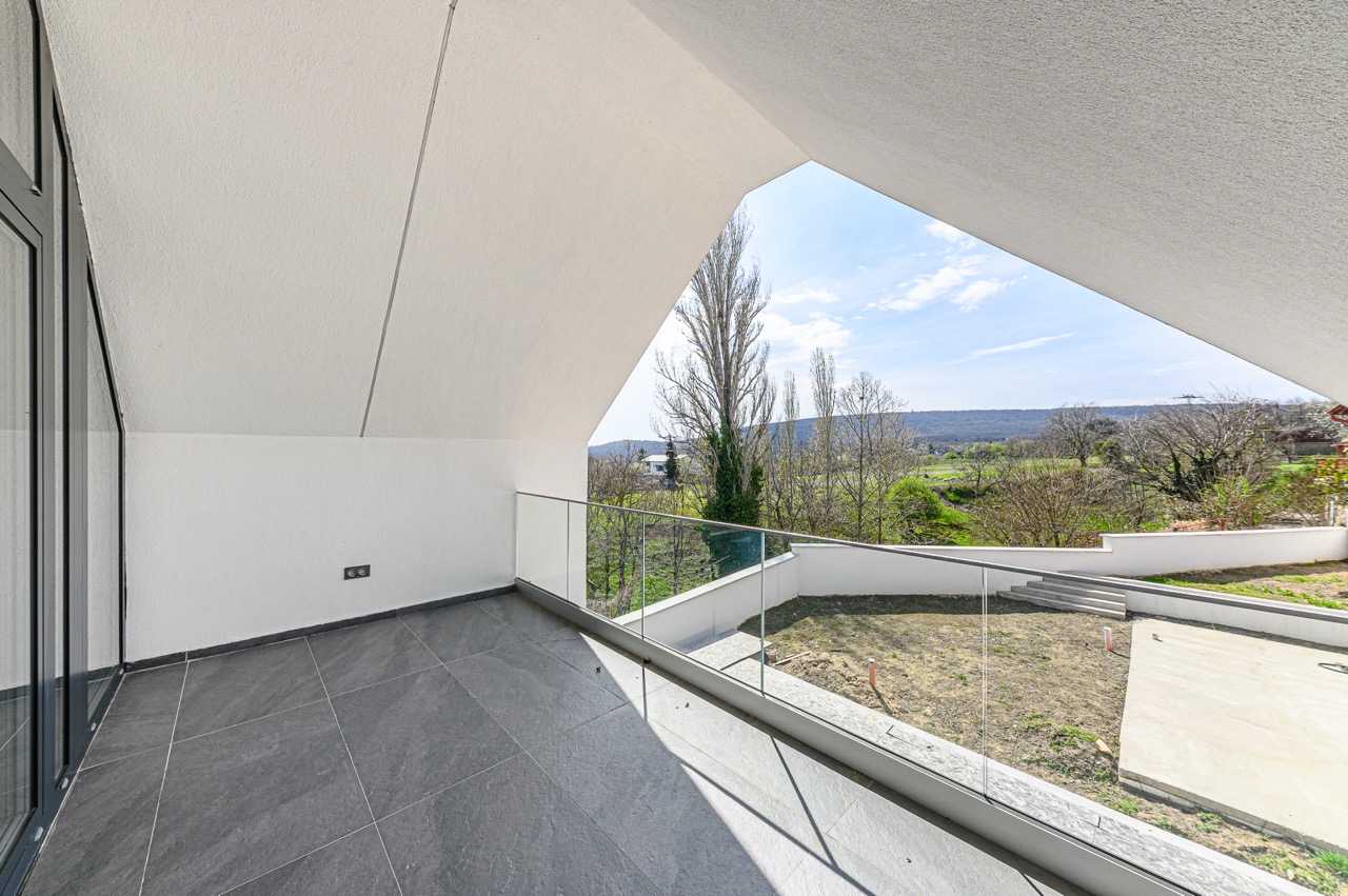 Modern terasz sötétszürke járólappal és üvegkorláttal, panorámás természeti kilátással