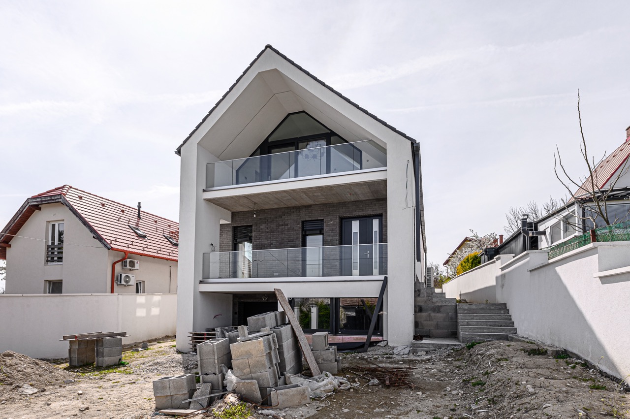 Modern családi ház homlokzata kétszintes erkéllyel és nagy üvegfelületekkel Balatonalmádiban