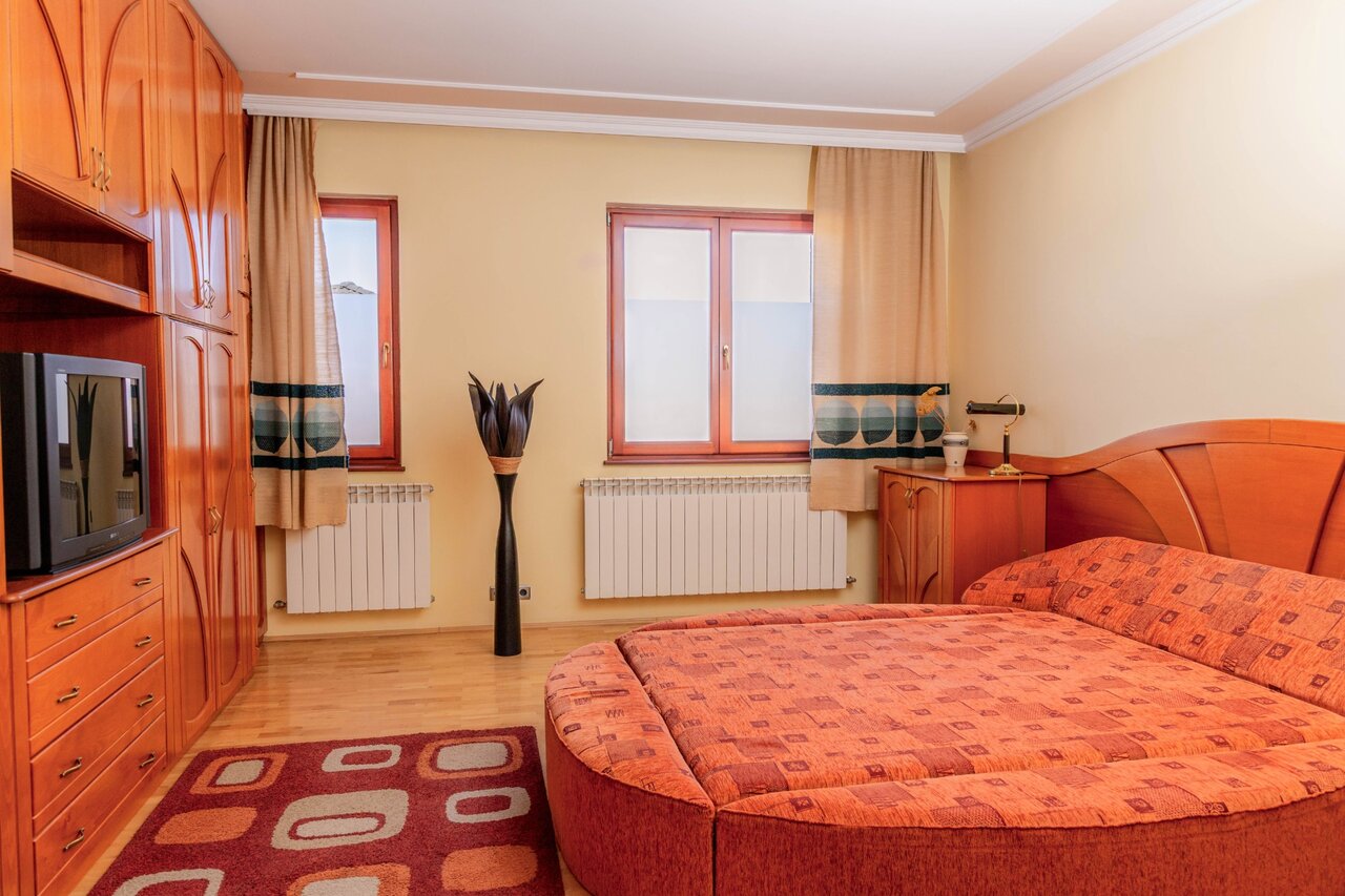 Hálószoba kerek ággyal és fa bútorokkal