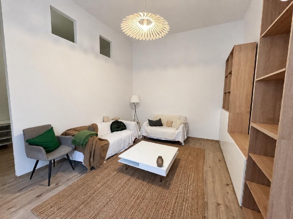 Világos, felújított nappali tölgy polcrendszerrel, kanapékkal és juta szőnyeggel - eladó lakás a Corvin-negyedben, Budapest VIII. kerület