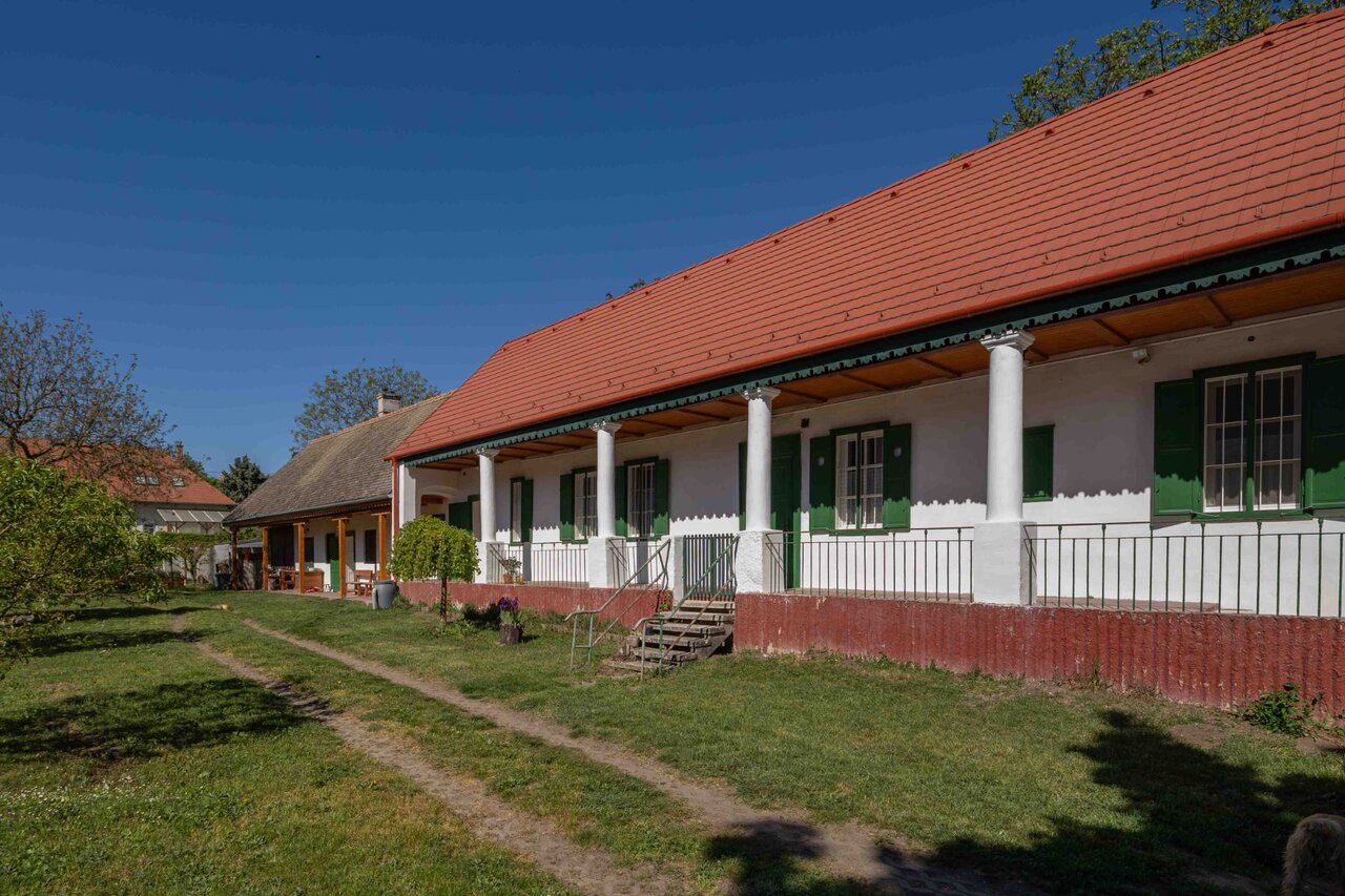Hosszú, oszlopos tornác és gondozott füves udvar