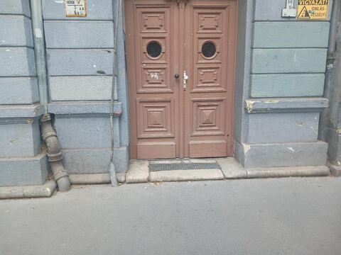 Kopott épülethomlokzat barna fa bejárati ajtóval