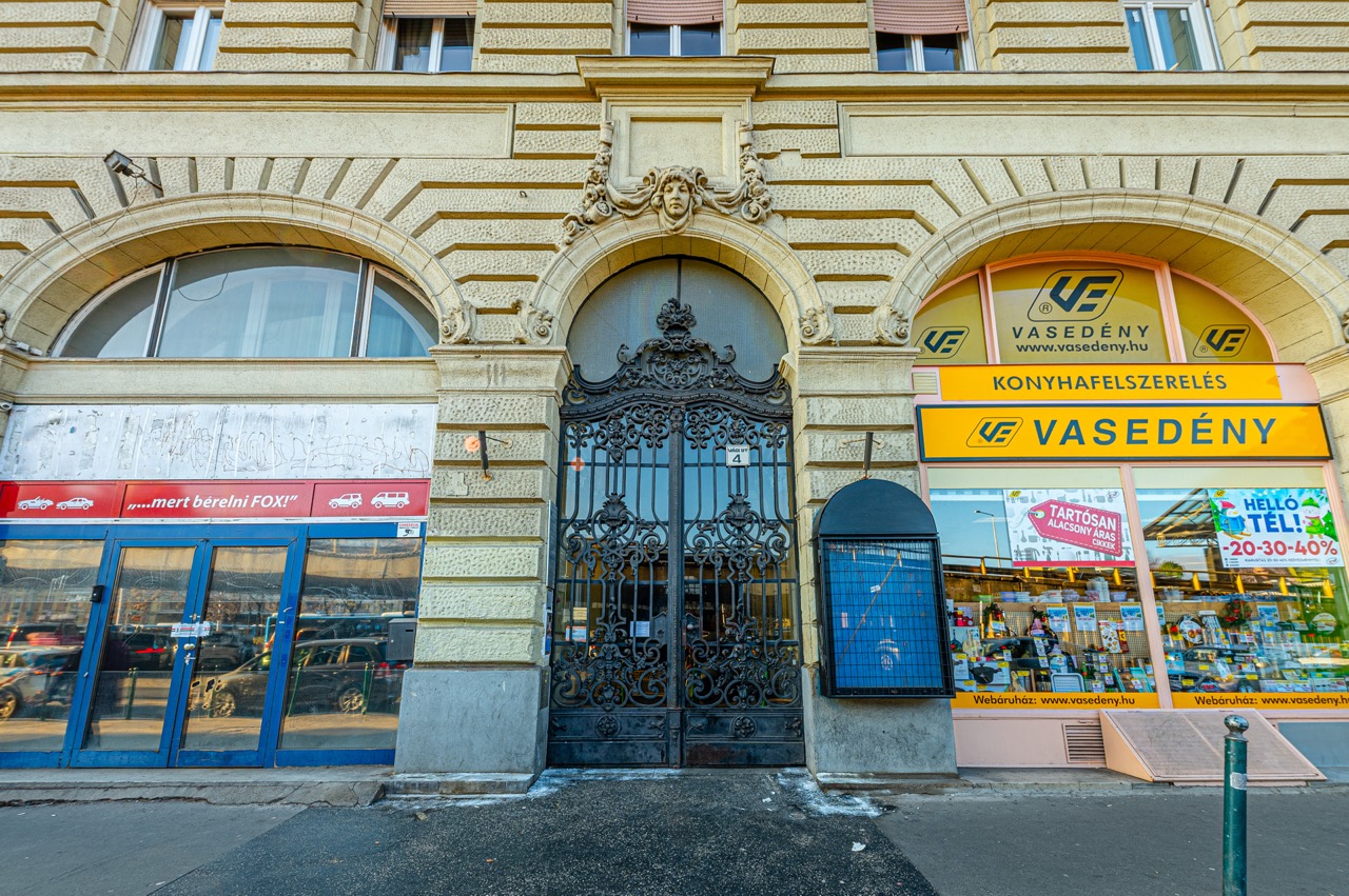 Az épület klasszikus homlokzata díszes kapuval és üzlethelyiségekkel