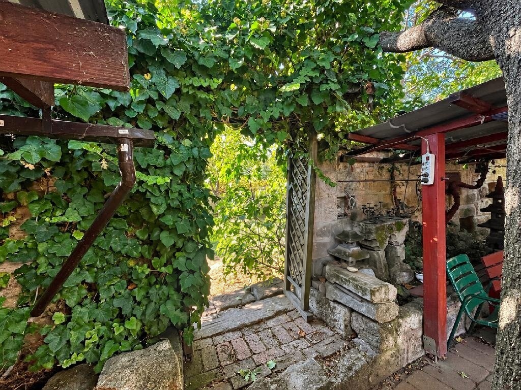 Lugas és fedett pihenőhely a kertben régi kőfalakkal