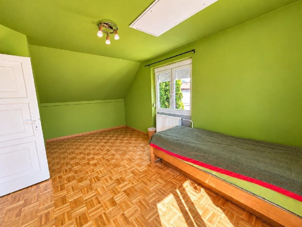 Zöld falú, tetőtéri hálószoba parkettával és redőnyös ablakkal