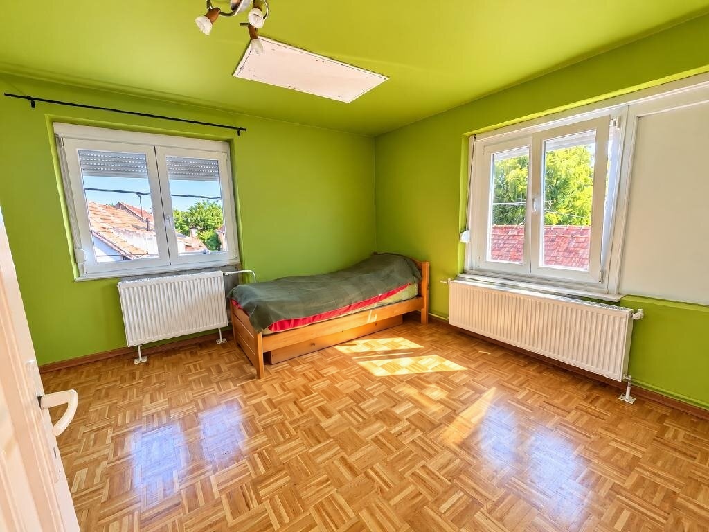 Zöld falú hálószoba parkettával és két redőnyös műanyag ablakkal