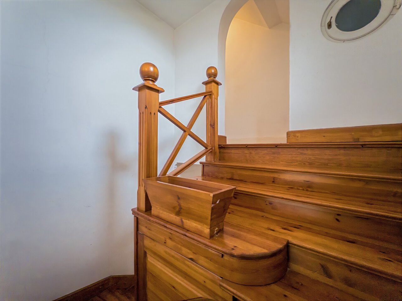 Világos lépcsőház masszív fa lépcsővel, korláttal, boltívvel és kerek ablakkal - Városmajor, Budapest XII. kerület
