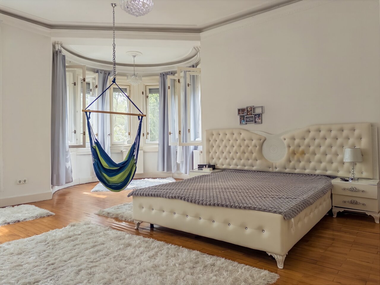 Tágas, világos hálószoba kárpitozott franciaággyal, függőfotellel az öbölablaknál és csillárral - Városmajor, Budapest XII. kerület