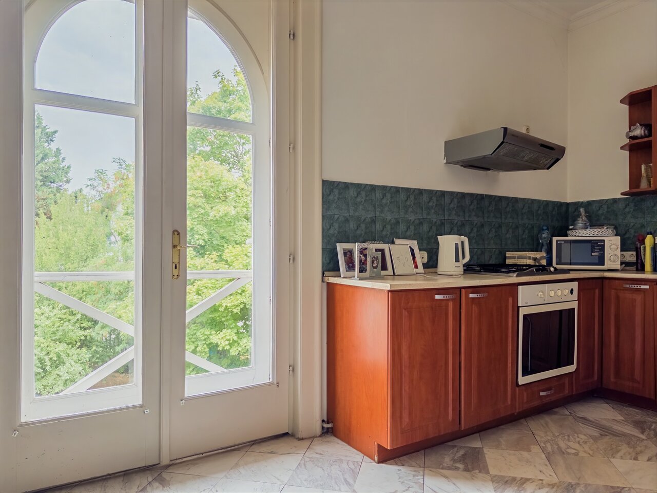 Világos konyha beépített konyhabútorral, sütővel és nagy íves üvegajtóval a szabadba - luxusvilla a Városmajorban, XII. kerület